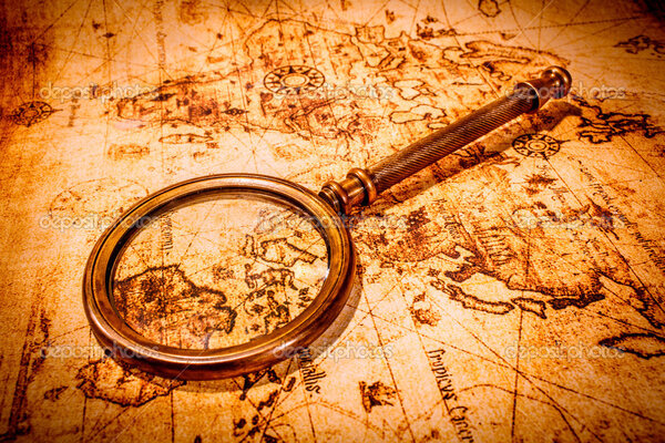 Vintage magnifying glass lies on an ancient world map